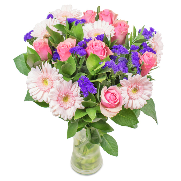 An elegantly composed floral arrangement from a Poplar florist, this bouquet captivates with its balance of soft and vibrant hues-ideal for any heartfelt local gesture. At its centre, around seven to nine pink roses, many delicately spiralled and in varying stages of bloom, stand as emblems of classic beauty and affection. These are complemented by five to seven pale pink gerbera daisies, each with expansive, soft petals radiating from creamy centres, their gentle colour reminiscent of the sunrise over nearby the River Thames. Scattered among the focal blooms, clusters of bold purple statice or Limonium introduce lively contrast and tactile intrigue-mirroring the spirited patchwork of the Poplar community itself. Rich, deep green foliage forms a generous, layered base, its glossy leaves fresh from the morning's delivery, evoking the abundant green pockets found in Poplar parks. The transparent glass vase reveals a tangle of vibrant stems and crystal-clear water, lending the arrangement a natural, just-picked authenticity. Whether destined as a joyful birthday gift, an anniversary surprise, or a cherished Mother's Day offering within E14, the bouquet radiates gratitude and celebration. The interplay of colour, texture, and light reflects careful expertise and the local pride of Poplar's thriving floristry.